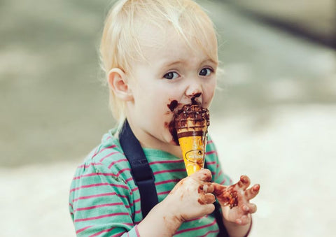 Kid eating a chocolate ice cream snack he is not supposed to eat. 