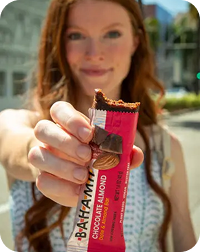 woman holding Bahama bar chocolate almond energy snack outdoors