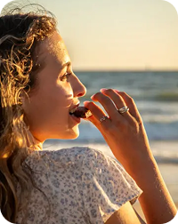 woman eating chocolate on beach at sunset