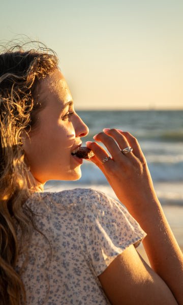 woman eating chocolate on the beach at sunset